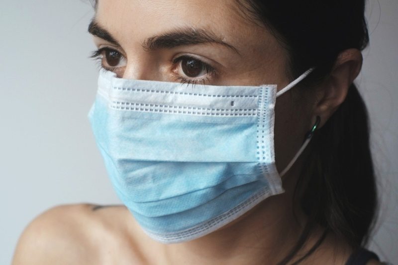 Fata care poarta o masca medicala albastra, de unica folosinta, pentru a se proteja impotriva coronavirusului