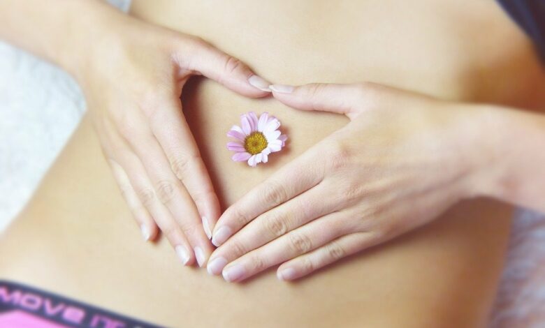 Femeie care cuprinde cu mainile o floare asezata pe stomac